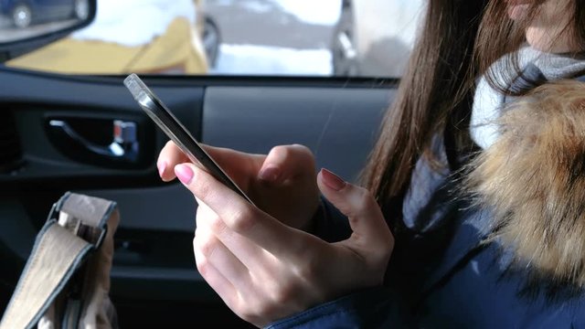 Woman in a car with a mobile phone. Closeup woman's hands chatting in phone.