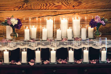 Decoration on the table: candles in glasses, purple flowers in vases