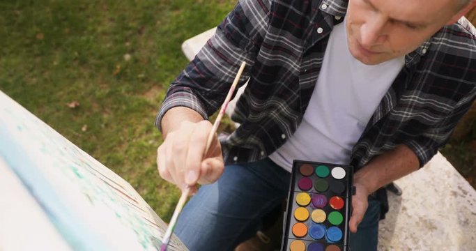 Man painting on canvas in the garden