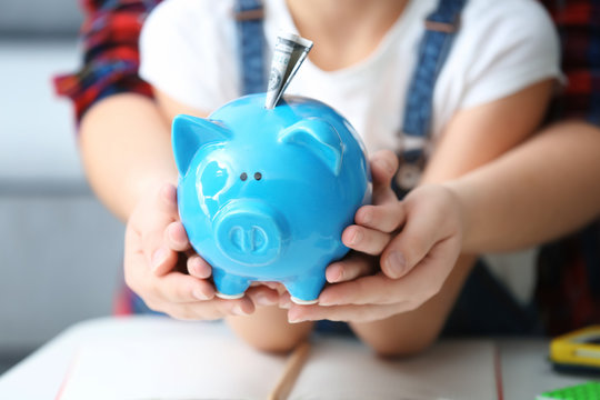 Mother and her little daughter holding piggy bank, closeup