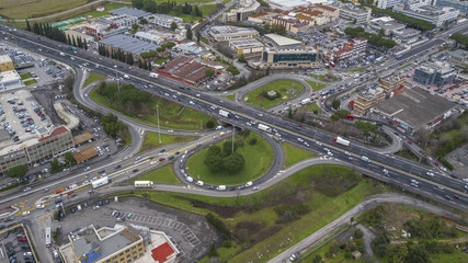 Aerial view of a series of highway ramps for immission or exit from the highway at high speed. So many cars, motorcycles, trucks are running on this road near a big city and an industrial area.