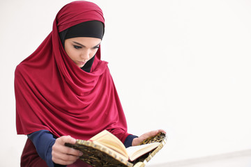 Young Muslim woman reading Koran, indoors