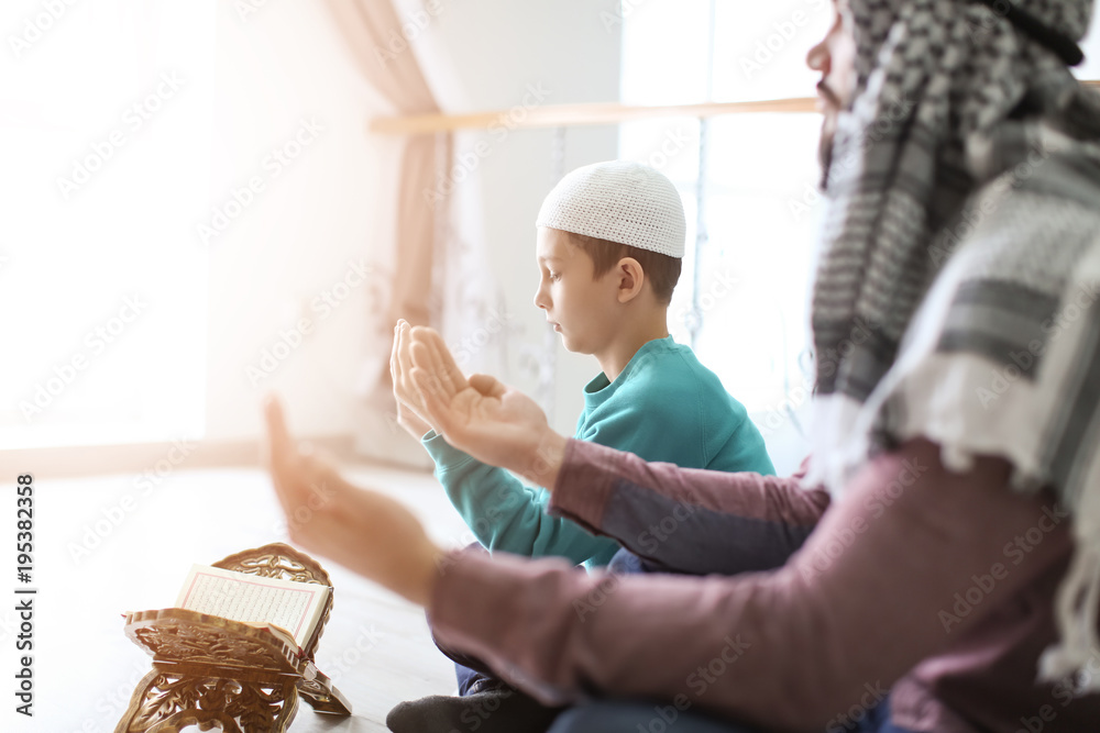 Wall mural muslim father and son praying together, indoors