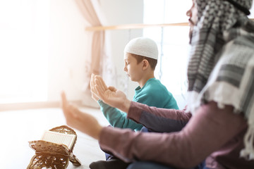 Muslim father and son praying together, indoors