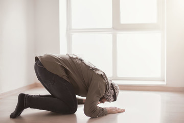 Young Muslim man praying, indoors