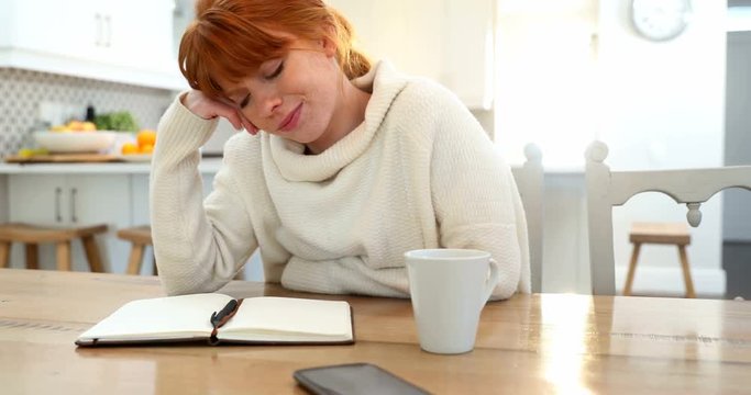 Beautiful woman writing in organizer at table 