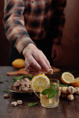 Ginger tea with brown sugar , lemon and mint on old wooden table .