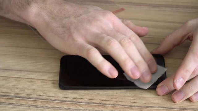 Close-up. Preparing the screen for a new mobile phone. Cleaning with a damp cloth. New protective, chopped, shockproof glass.