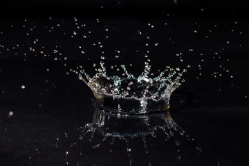 drop of water liquid with splash isolated. the drop explodes in the water sending spray to the sides and circle ripples around it. the water is blue