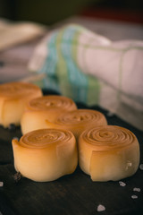 Few smoked cheese rolls on dark wooden board with spice around