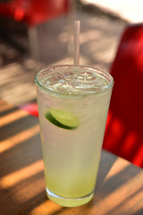 glass of lemonade with lime slice on outdoor patio table