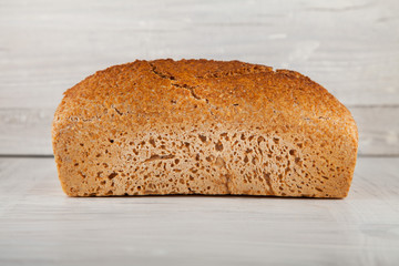 fresh wholegrain bread on white wooden kitchen table can be used as background