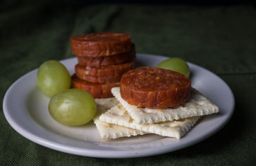 Pepperoni, grapes, and crackers on a snack plate