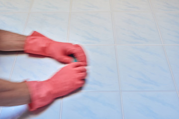 Hands in protective rubber gloves using sponge for cleaning, natural motion blur