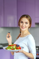 Obraz na płótnie Canvas Smiling young girl eating vegetable salad. The concept is healthy food, diet, vegetarianism, weight loss.