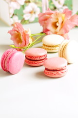 macaroons in pastel colors with flowers on a pale pink background.Holiday background.copy space