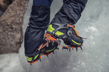 Naklejka premium Climber on a frozen waterfall. Crampons close-up on his feet ice climber
