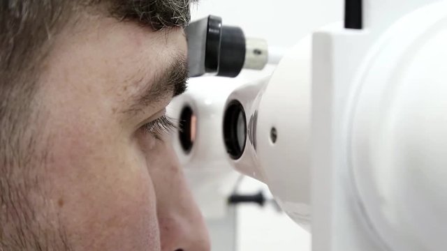 Patient in ophthalmology clinic. Man looks in synoptophore - ophthalmic instrument, used for diagnosing imbalance of eye muscles and treating them by orthoptic methods, for treatment of strabismus