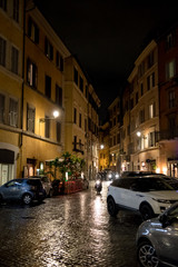 Fototapeta na wymiar Beleuchtete enge Straße bei Nacht in Rom in Italien