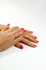 Two female hands in elegant pose with pale pink painted nails on a white surface