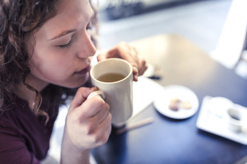 portrait of a young woman drinking a herbal tea and looking around
