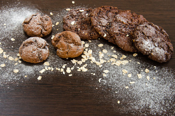 Cookies with chocolate on dark background with sugar powder, oat flakes and seasame