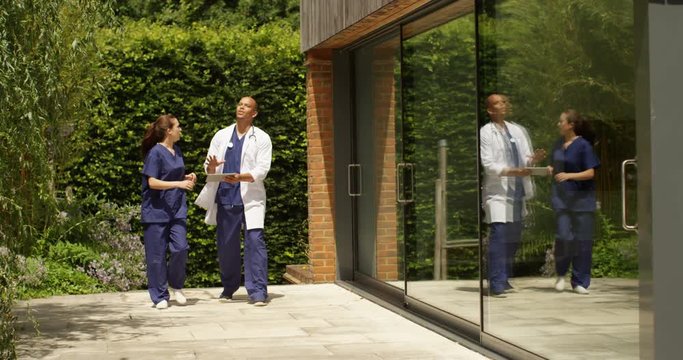 4K Medical workers with digital tablet arguing outside modern hospital building. Slow motion