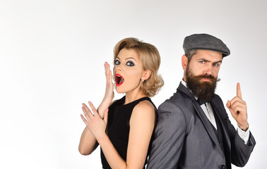 Portrait of couple in retro clothes. Fashionable couple. Surprised woman in black dress and serious bearded man in grey suit. Isolated on white background.