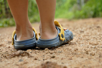 Boy wearing sandals prepare to walk along the dirt road.