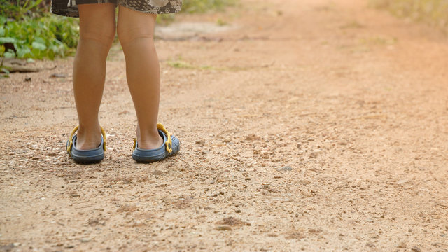 Boy wearing sandals prepare to walk along the dirt road.