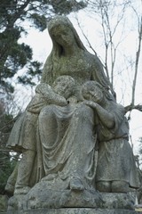 Fototapeta na wymiar old carved stone figure on grave women gravestone in graveyard, memorial angel on tombstone