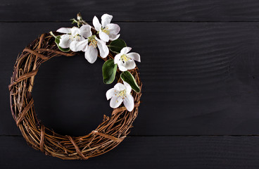 Wreath with spring flowers on a dark wooden background.