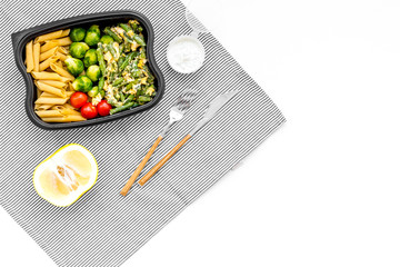 Healthy and hearty lunch for office worker. Vegetables Brussels sprout, cherry tomatoes, knock beans near pasta in plastic container on white background top view copy space