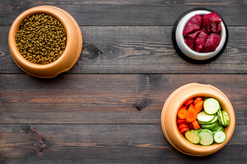 Ingredients for dry pet food. Meat and vegetables zucchini and carrot on dark wooden backgroud top view copy space