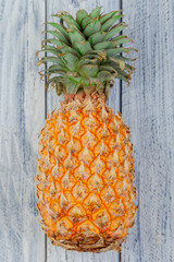 one big whole pineapple on a light wooden background with copyspace