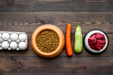 Dry food for dogs and cats based on raw meat and vegetables on dark wooden backgroud top view copy space