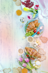 Background Easter. For breakfast Croissants with salad and espresso. Fresh juice and sweets. Spring tulips. Easter decor. White wooden background.