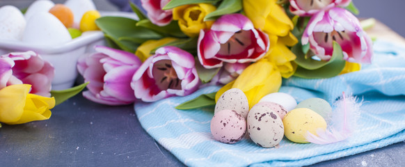 A bouquet of fresh spring tulips of pink and yellow color. Buds. Eggs for Easter are different colors. Bouquet as a gift