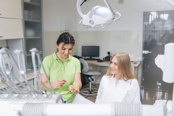 The dentist teaching a girl oral hygiene on braces in a dental clinic.