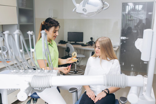 The dentist teaching a girl oral hygiene on braces in a dental clinic.