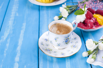 Ice cream of different colors on a blue background. Raspberries and mango. Decor of flowers and morning coffee. Free space for text