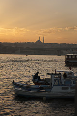 Fototapeta na wymiar Fishing boat and fisherman silhouette at sunset in Karakoy, Golden horn, istanbul