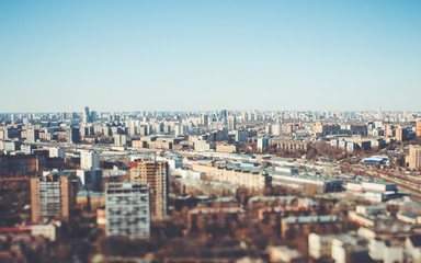 Fototapeta na wymiar True tilt-shift view form hight point of the urban cityscape: a residential district with many houses of different size and color, cold bright day with blue sky, focus in the middle of the image