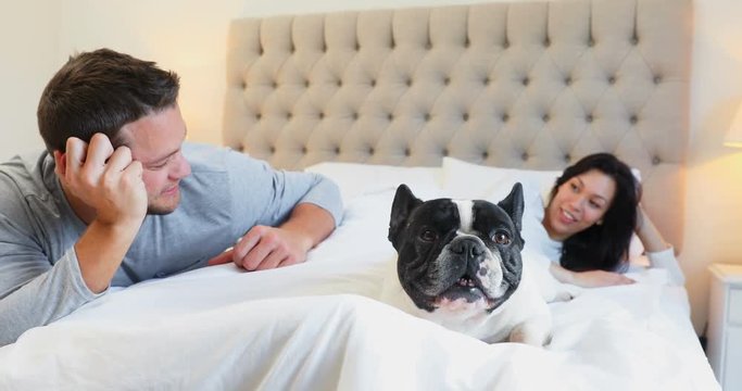 Couple with pug dog interacting with each other on bed