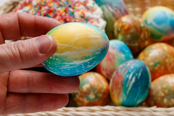 In his hand is an Easter egg. Against the background of Easter cakes and colorful Easter eggs.