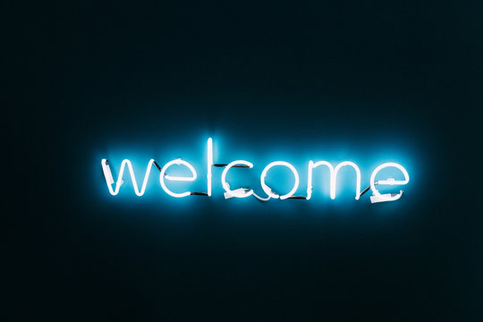 Welcome neon sign on brick wall background