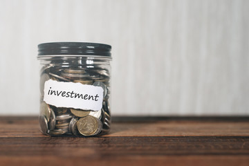 coins in a jar with label written INVESTMENT. financial concept