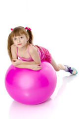 little girl doing exercises on a big ball for fitness.