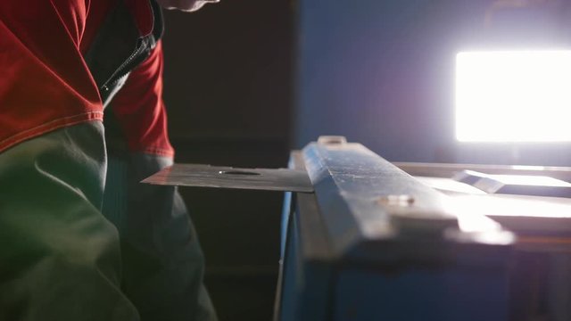Worker bending the flat metal part with a special manual machine