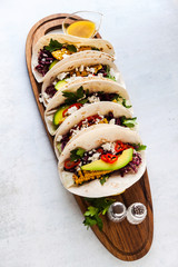 Mexican tacos with avocado, grilled corn, red cabbage slaw and chili salsa on wooden board black shale table. Recipe for Cinco de Mayo party. Top view. Copy space background